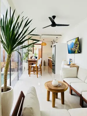 a living room with white furniture and a palm tree at Villa Karma Damai in Seminyak