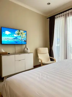 a bedroom with a bed and a tv on a wall at Villa Karma Damai in Seminyak