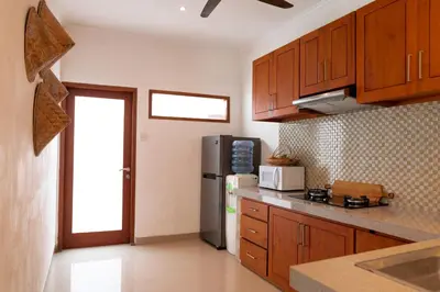 a kitchen with wooden cabinets and a refrigerator at Villa Lima Legian in Seminyak