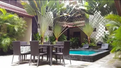 a patio with a table and chairs and a pool at Cempaka Apartment Surfaris Inn in Legian