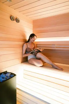 a woman sitting in a sauna reading a book at The Suaka Baliaga by Puri Asia in Seminyak