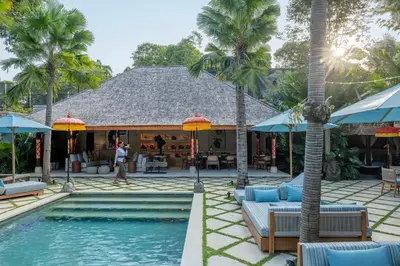 a resort with a swimming pool and palm trees at The Suaka Baliaga by Puri Asia in Seminyak