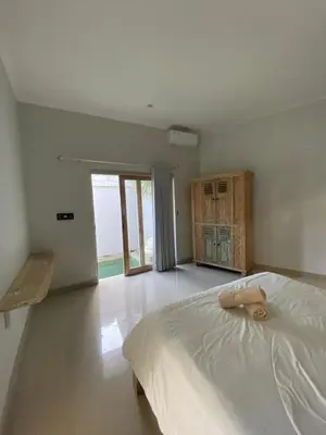 a white bedroom with a bed and a large window at Two spacious bedroom villa in Seminyak