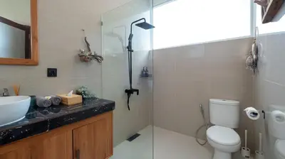 a bathroom with a shower and a toilet and a sink at Villa Lange 3 by Villa Finder in Seminyak