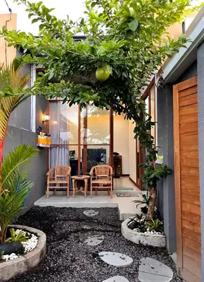 a patio with two chairs and a table and trees at Villa Teras Asri Seminyak in Denpasar