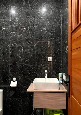 a bathroom with a sink and a black marble wall at Villa Teras Asri Seminyak in Denpasar