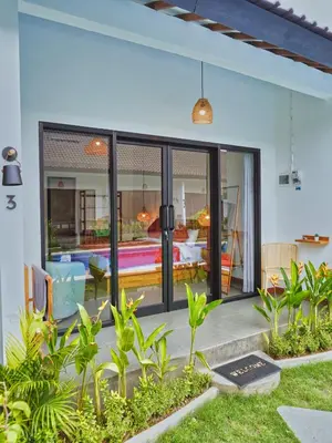 an open pivot door of a home with a patio at Mistral Studio Umalas in Canggu