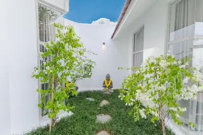 a man sitting on the side of a white house at Villa Cocodrilos 2 by Pertama Management in Seminyak