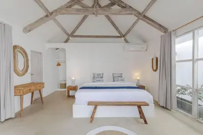 a white bedroom with a large bed and a table at Villa Cocodrilos 2 by Pertama Management in Seminyak