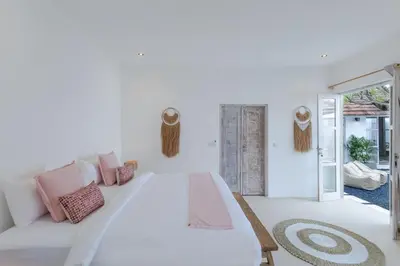 a white bedroom with a large bed with pink pillows at Villa Cocodrilos 2 by Pertama Management in Seminyak