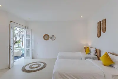 a white room with two beds and an open door at Villa Cocodrilos 2 by Pertama Management in Seminyak