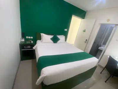 a bedroom with a large bed with a green wall at AI Hotel Kuta - 15 Second to the Beach and 1 Minute to Airport by Micky Studio in Ngurah Rai International Airport