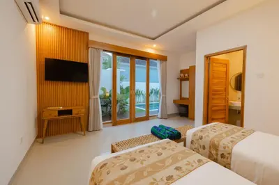a hotel room with two beds and a flat screen tv at Arvi Villa Pandawa Legian in Legian