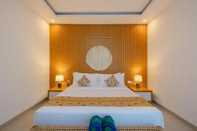a bedroom with a bed with two lamps and blue slippers at Arvi Villa Pandawa Legian in Legian