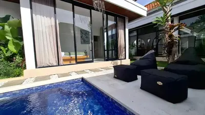 a house with a swimming pool in front of a house at Modern Tropical 2 Bedroom Villa Ocean Nest in Canggu