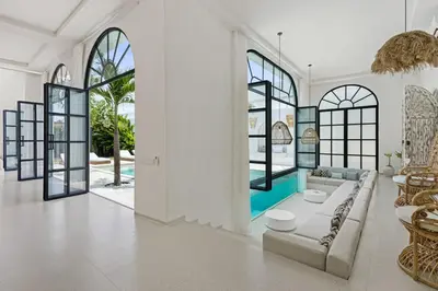 a living room with a couch and some windows at All-White Villa with Pool, Sauna, Firepit & Office in Jimbaran