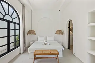 a white bedroom with a bed and a table at All-White Villa with Pool, Sauna, Firepit & Office in Jimbaran