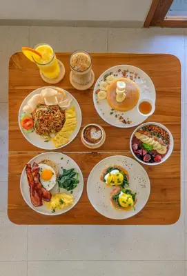 a wooden table with plates of breakfast food on it at Kuta Beach Villas by Great Bali Villas in Badung