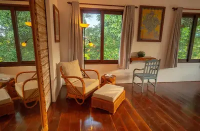 a living room with chairs and a table and windows at The Sundara Room in Kerobokan