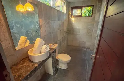 a bathroom with a toilet and a sink and a mirror at The Padma Room in Kerobokan