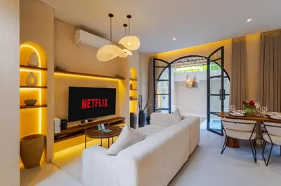 a living room with a white couch and a tv at Villa Santa Clara by Pertama Management in Seminyak
