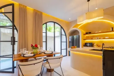 a kitchen with yellow walls and a wooden table and chairs at Villa Santa Clara by Pertama Management in Seminyak