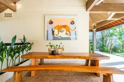 a wooden bench in a room with a painting of a leopard at The Hijau Damai Villa in Seminyak