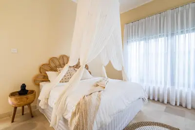 a bedroom with a bed with white sheets and a window at The Hijau Damai Villa in Seminyak
