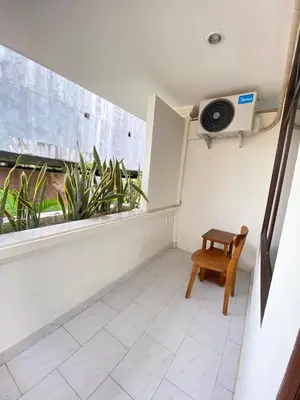 a room with a window with a chair and a fan at SH Hotel - 20 Second to the Bach by Micky Studio R in Legian