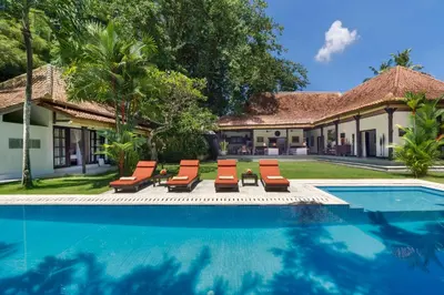 a swimming pool with lounge chairs and a house at Villa Delapan Seminyak in Seminyak