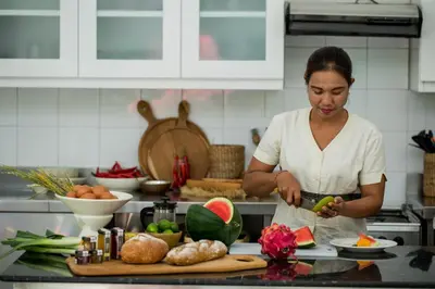 a woman standing in a kitchen preparing food at Villa Delapan Seminyak in Seminyak