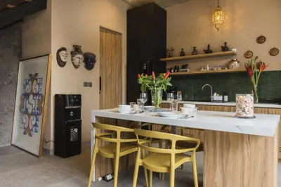 a kitchen with a bar with yellow stools at DUNE Villas in Seminyak