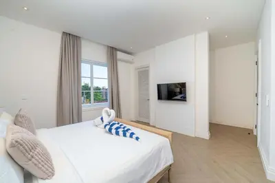 a white bedroom with a large bed and a tv at Villa Aclasa Luxery 4BR Retreat in Berawa, Canggu in Canggu