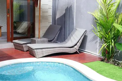a patio with a chair and a swimming pool at Villa Mannah - Managed By Chayah Bali Villa Group in Kuta