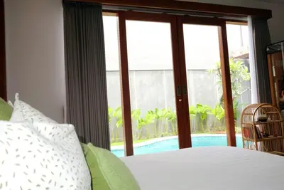a bedroom with a bed and a large window at Villa Mannah - Managed By Chayah Bali Villa Group in Kuta