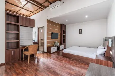 a bedroom with a bed and a desk and a television at Villa Nakula - Managed By Chayah Bali Villa Group in Seminyak