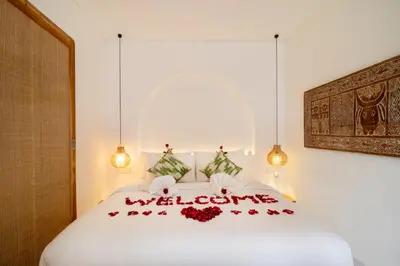 a white bed with red flowers on it at Brand New Villa 2BR with Private Pool near Seminyak by BaliSuperHost in Seminyak
