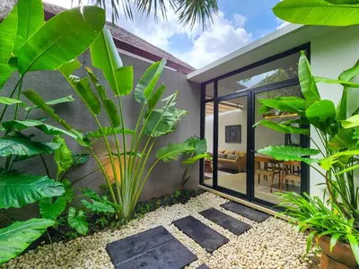 a tropical garden with plants and a house at Silk Umalas by Nagisa Bali in Kerobokan
