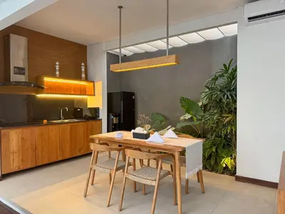 a kitchen with a wooden table and chairs at Silk Umalas by Nagisa Bali in Kerobokan