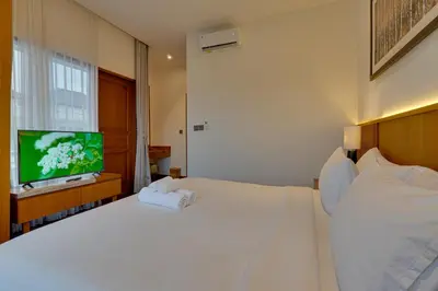 a bedroom with a white bed and a flat screen tv at New! Villa Taman Seminyak 01 near Double Six Beach in Seminyak