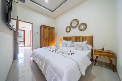 a bedroom with a white bed with roses on it at Jimbaran Retreat in Jimbaran