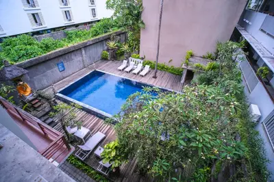 an overhead view of a swimming pool with chairs and trees at Kamini Legian Hotel in Legian