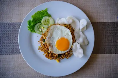 a plate of food with an egg and noodles at Kamini Legian Hotel in Legian