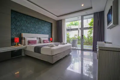 a bedroom with a large bed and a large window at Kamini Legian Hotel in Legian