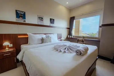 a bedroom with a large white bed with a window at Homely Bali at Seminyak in Kerobokan