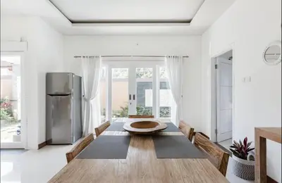 a dining room with a table and a refrigerator at Walk to Beach - Private 3 Bedroom Villa Roshi Seminyak in Seminyak