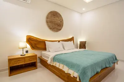 a bedroom with a large bed with a wooden headboard at Mirragold Villa - Sun, Pool and Views - Brand New 3BDR Villa in Kerobokan