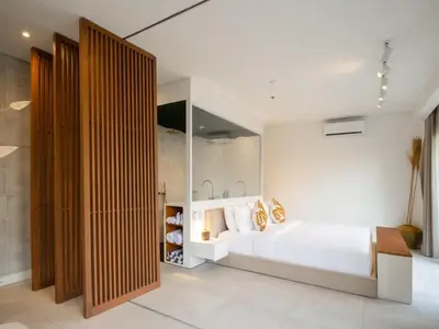 a bedroom with a large white bed and wooden walls at Berawa Luxury Retreat - The Cruise Canggu in Canggu
