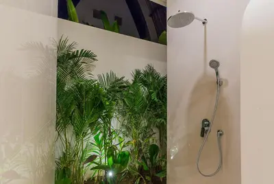 a bathroom with a shower with plants on the wall at Villa Trindade 5BR, 15m Pool in Seminyak