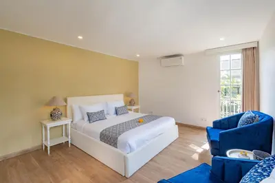a bedroom with a white bed and a blue chair at The Heritage 4BR Villa Luxury Oasis in Canggu